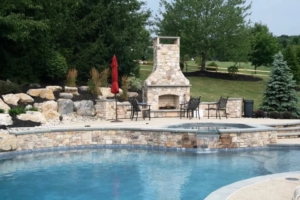 Outdoor-fireplace-by-swimming-pool Stone fireplace overlooking stone-lined pool